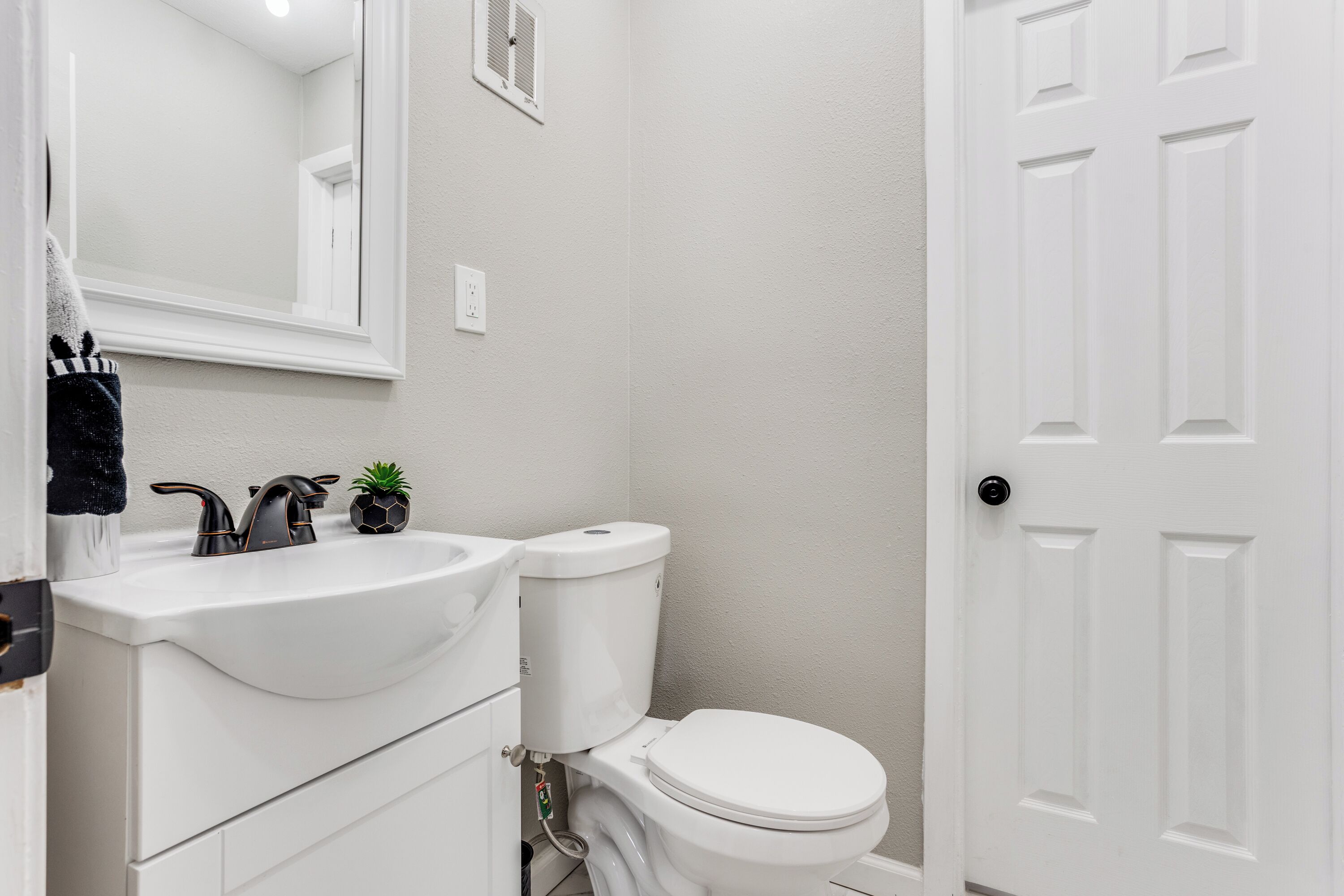A bathroom with a white sink, toilet, and door.