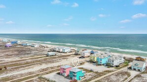Zona residencial costera con casas cerca de la playa, cielo despejado y mar tranquilo.