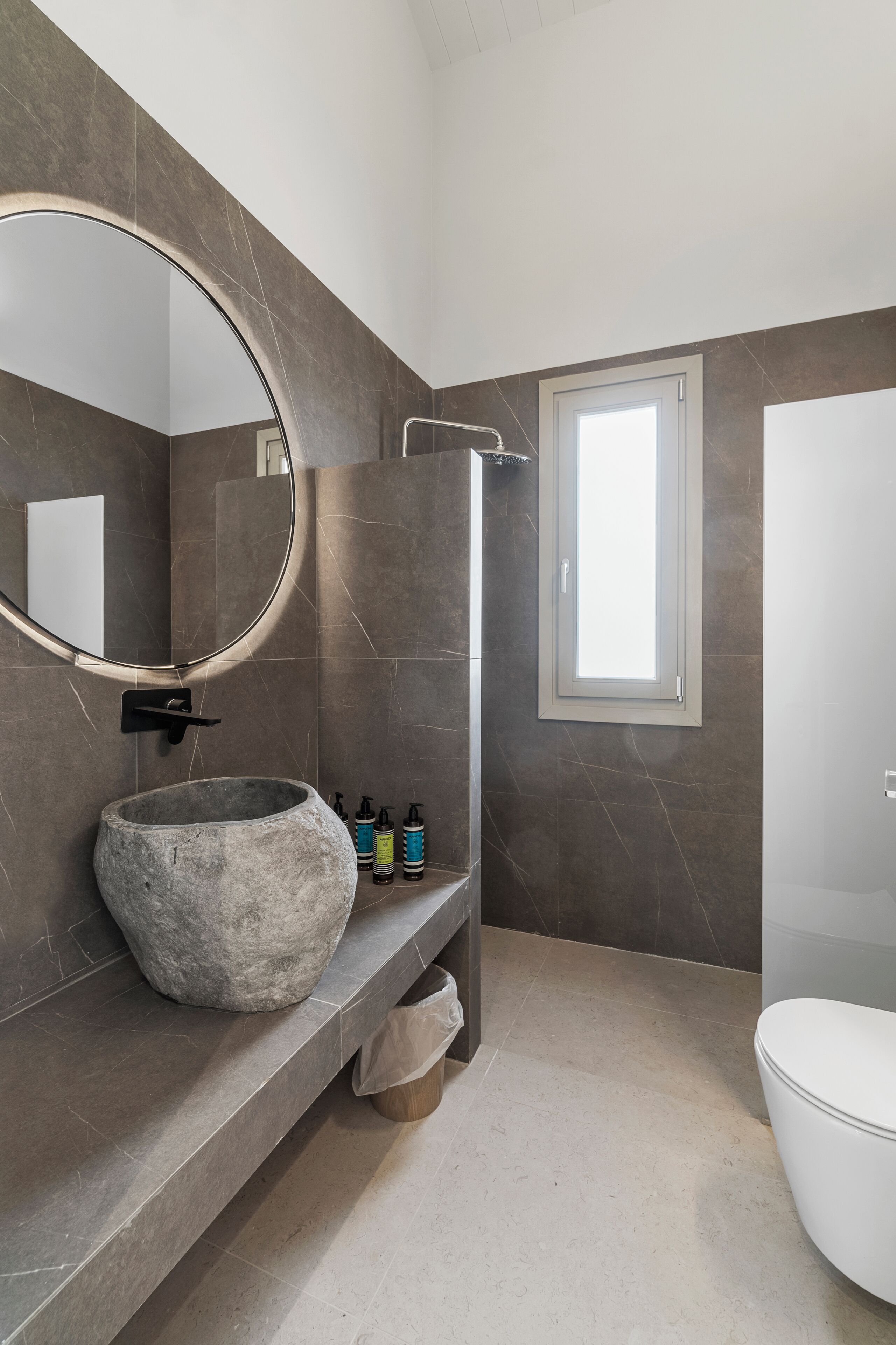 A bathroom with a stone sink, a shower, and a toilet.