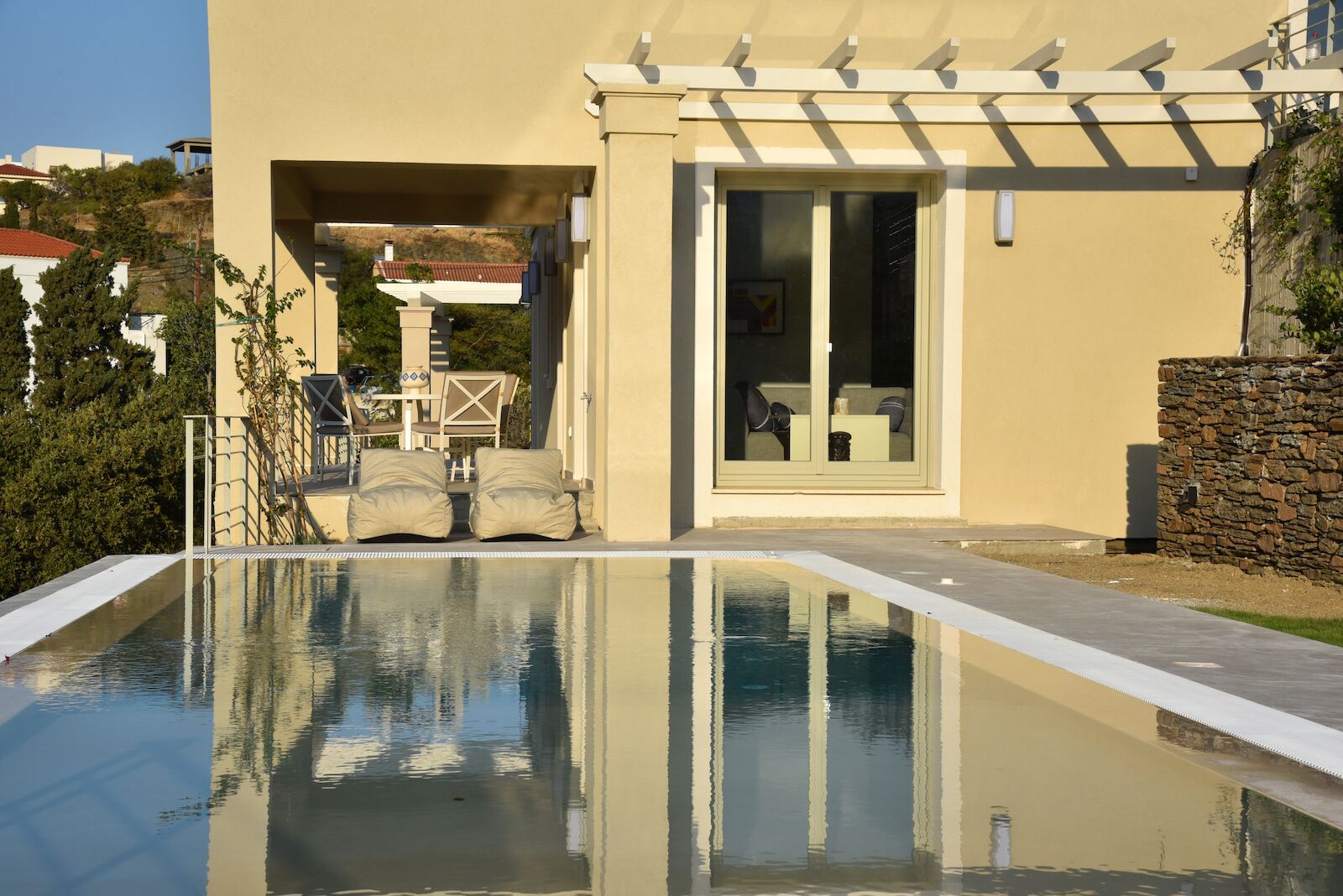 Une maison moderne dotée d’une piscine, de mobilier d’extérieur et d’un mur en pierre.
