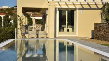 Une maison moderne dotée d’une piscine, de mobilier d’extérieur et d’un mur en pierre.