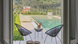 Un balcon donnant sur une piscine et une colline.