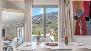 Un espace de restauration moderne, doté d’une grande table, de chaises et offrant une vue sur un paysage montagneux grâce à de larges fenêtres.