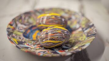 Three colorful glass ornaments on a patterned plate.