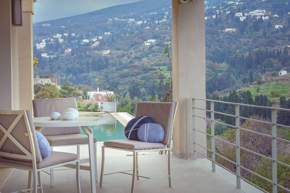 Varanda com piscina, duas cadeiras e uma mesa.
