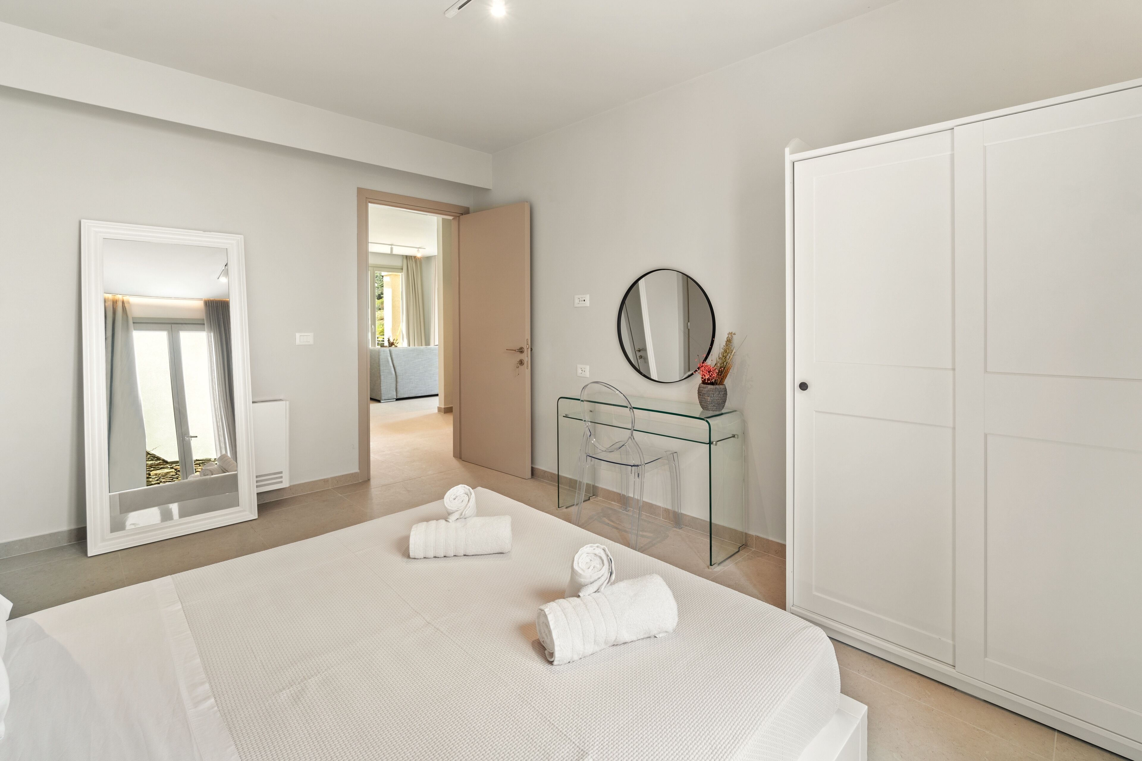 Een moderne hotelkamer met een groot bed, een glazen bureau, een kledingkast en een spiegel.