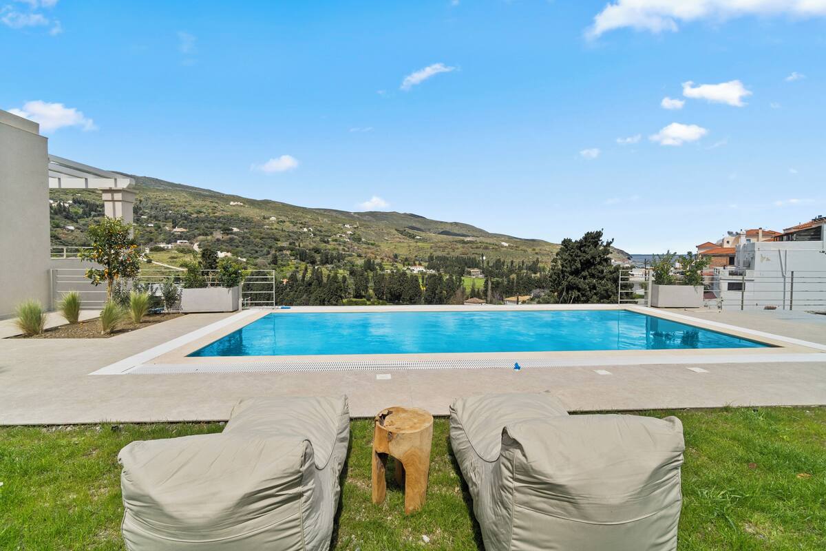 Piscina com espreguiçadeiras e vista para uma paisagem montanhosa.