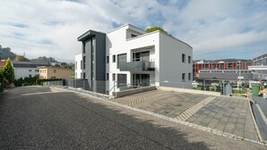 A modern building with a flat roof, large windows, and a balcony.