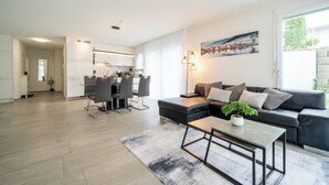 A modern living room with a sofa, coffee table, and dining area.