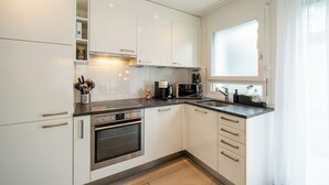 A modern kitchen with white cabinets, a built-in oven, a microwave, and a coffee maker.