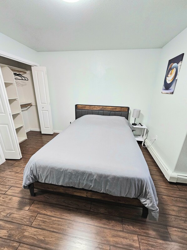Un dormitorio con una cama, un armario y una mesita de noche.