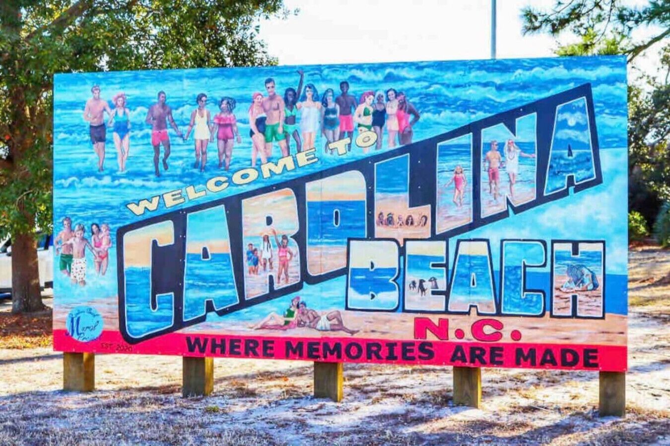 A welcome sign for Carolina Beach, N.C., featuring a beach scene with people and the text "WHERE MEMORIES ARE MADE".