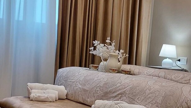 Ein Hotelzimmer mit einem Bett, einer Bank, einem Nachttisch mit Lampe und einer dekorativen Vase.