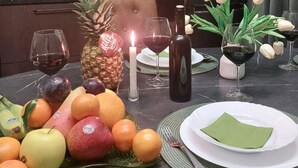 Ein Esstisch mit Obst, Weingläsern, einer Kerze und einer Flasche.