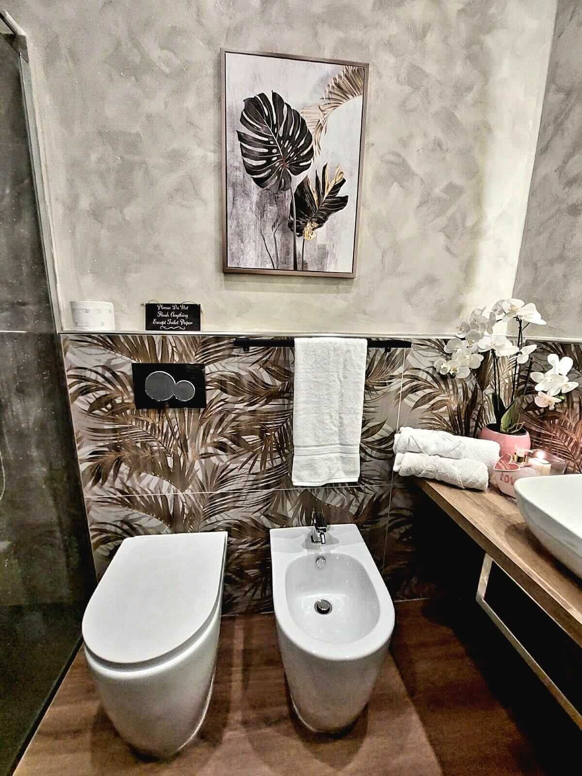 A modern bathroom with two bidets, a large mirror, and a decorative plant.