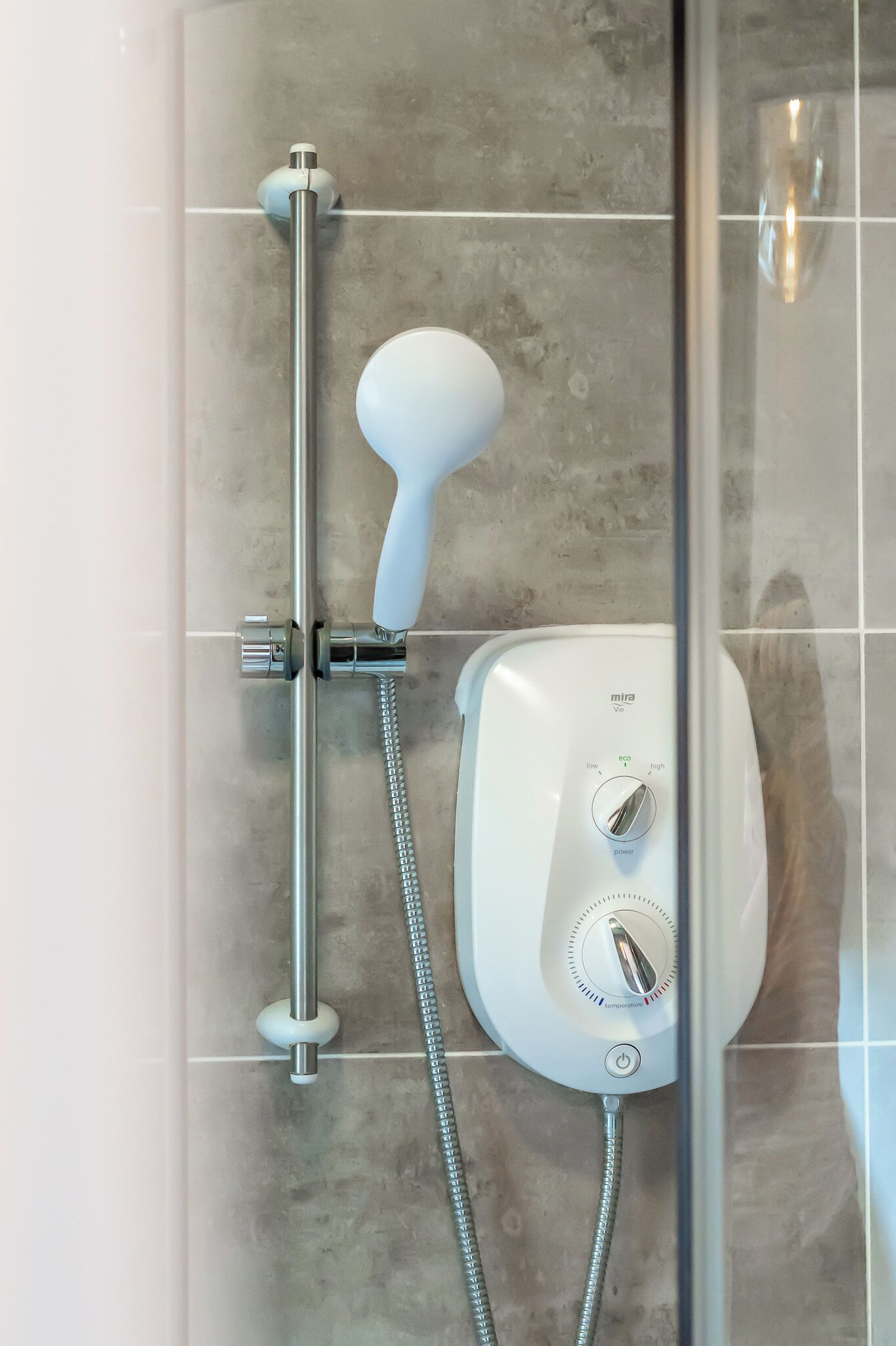 Une douche moderne dotée d’un pommeau de douche à main et d’un panneau de commande fixé au mur.
