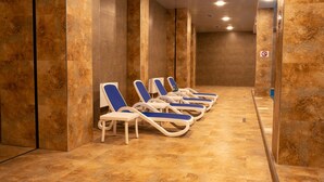 Filas de tumbonas en un espacio de spa con paredes y suelos de mármol.