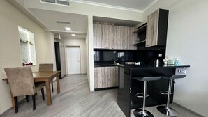 Una cocina moderna con armarios de madera, encimera negra y una barra con taburetes.