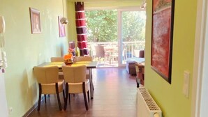 A spacious room with a dining area, a large window, and a radiator on the wall. - House directly on the beach, behind the dune, sea view (Breege)