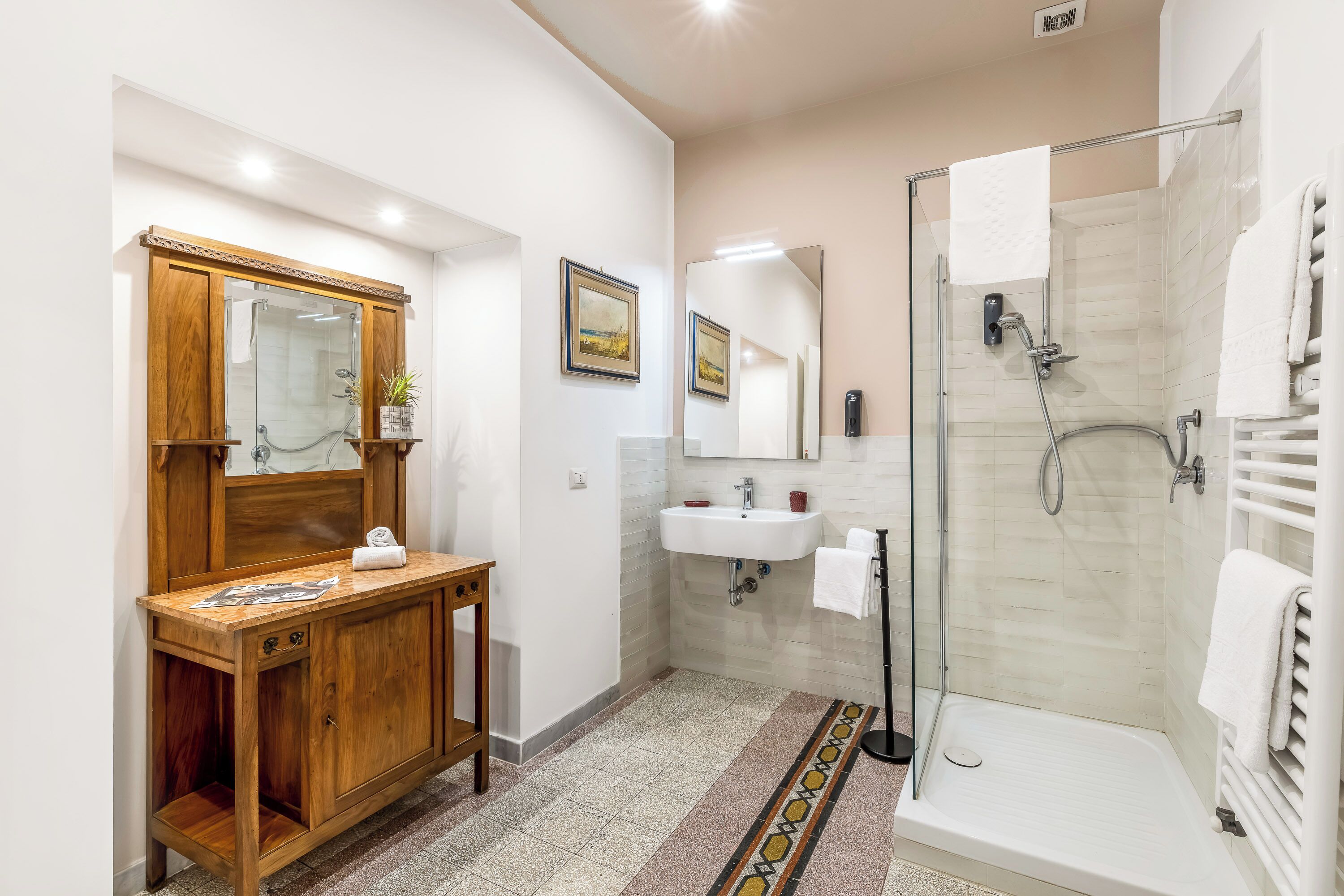A modern bathroom with a wooden vanity, a glass shower enclosure, and a white bathtub.