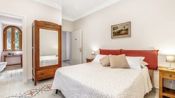 Un dormitorio con una cama grande, mesitas de noche, un armario, un espejo y un cuadro en la pared.