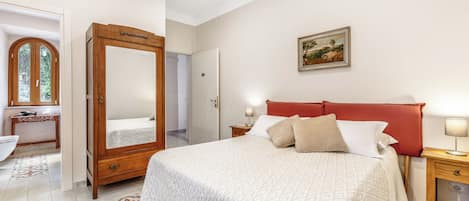 A bedroom with a large bed, bedside tables, a wardrobe, a mirror, and a painting on the wall.