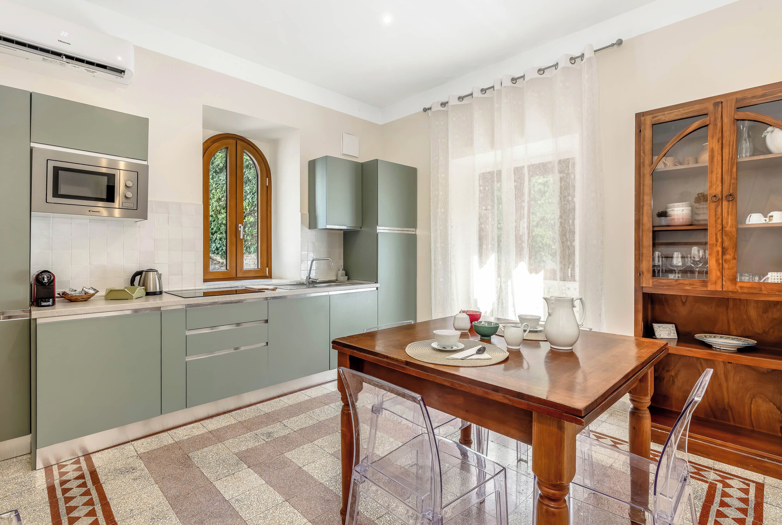 Una cocina moderna con microondas incorporado, hervidor de agua y mesa de comedor lista para cuatro personas.