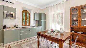 Una cocina moderna con microondas incorporado, hervidor de agua y mesa de comedor lista para cuatro personas.