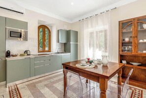 A modern kitchen with a built-in microwave, a kettle, and a dining table set for four. - TorripaCollection - Villa Falisca - Bolsena Lake (Montefiascone)
