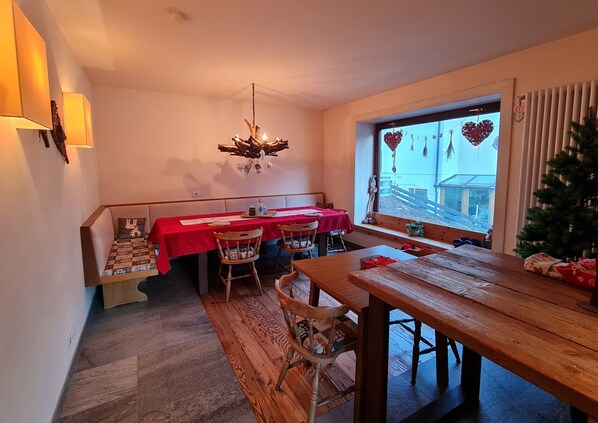 A dining area with a wooden table and chairs, a red tablecloth, and a chandelier. - Mountain-view Apartment in Bad Kleinkirchheim (Bad Kleinkirchheim)