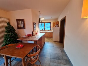 A kitchen with wooden cabinets, a wooden dining table with chairs, a small Christmas tree, and a refrigerator. - Mountain-view Apartment in Bad Kleinkirchheim (Bad Kleinkirchheim)