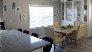 A kitchen with a granite countertop, a dining table with chairs, a ceiling fan, and a window with blinds. - Charming 2-bedroom apartment with shared Pool, frontyard WiFi, AC (St. Petersburg)