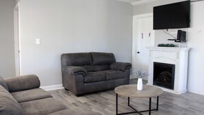 A living room with a gray sofa, a round coffee table, and a fireplace. - Charming 2-bedroom apartment with shared Pool, frontyard WiFi, AC (St. Petersburg)