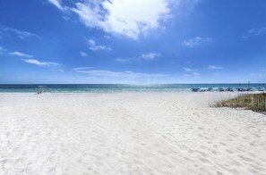 Una playa de arena blanca y aguas azules cristalinas bajo un cielo despejado.