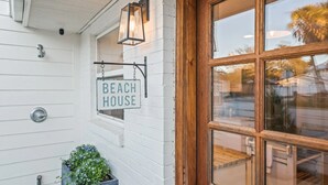 A white building with a sign reading "Beach House" and a wooden door. - New Golf Cart-Private Hot Tub-Walk to Beach-Charming Bungalow 4BR! (Santa Rosa Beach)