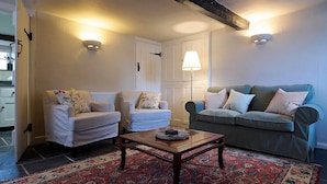 A living room with two armchairs, a sofa, a coffee table, and a patterned rug. - Church Cottage (Exeter)