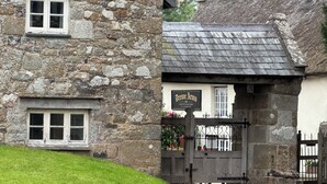 A stone building with a traditional thatched roof, a wooden door, and a sign reading "Drenne Arms." - Church Cottage (Exeter)