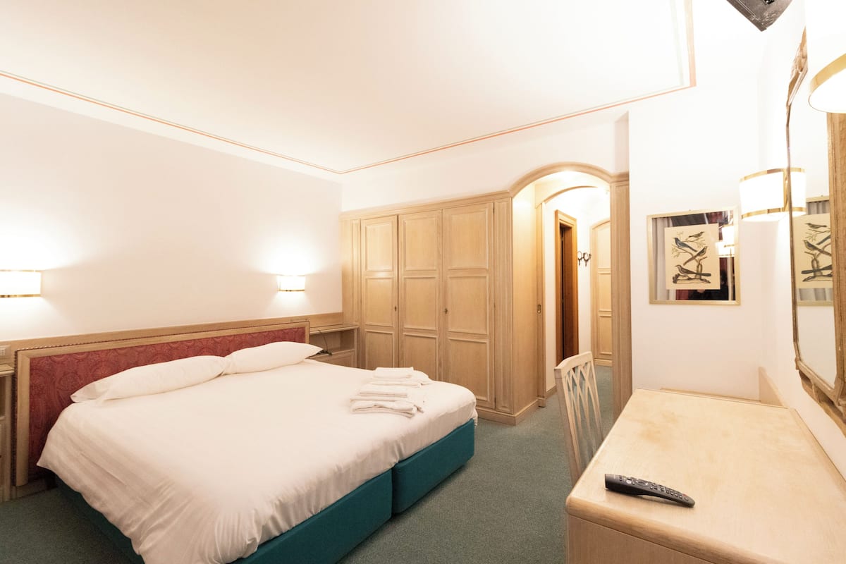 Ein Hotelzimmer mit Bett, Schreibtisch, Stuhl und Kleiderschrank.