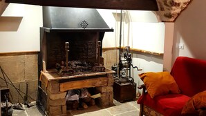 A stone-floored room with a fireplace, a red sofa, and a rustic ceiling. - Fully renovated 2 to 3 person gîte (Saint-Rome-de-Tarn)