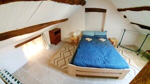 A bedroom with a bed, a nightstand, a small table, and a hanging light fixture. - Fully renovated 2 to 3 person gîte (Saint-Rome-de-Tarn)