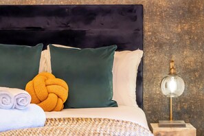 A neatly made bed with a dark headboard, a yellow knitted blanket, and a rolled white towel. - Sleek Studio Nest: Comfort in City Center (London)