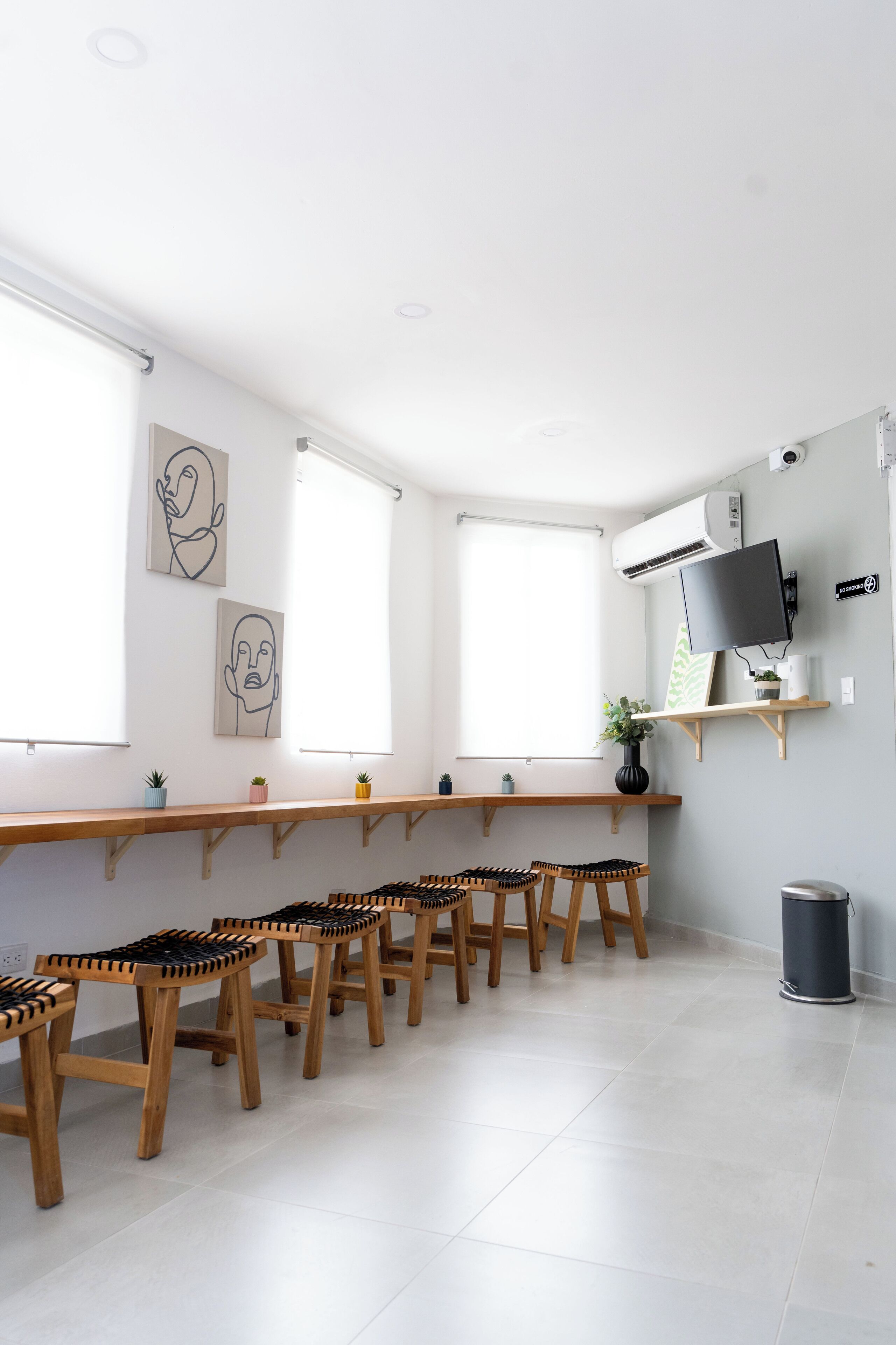 Una habitació moderna i ben il·luminada amb una taula de fusta llarga, diverses cadires i obres d'art a les parets.