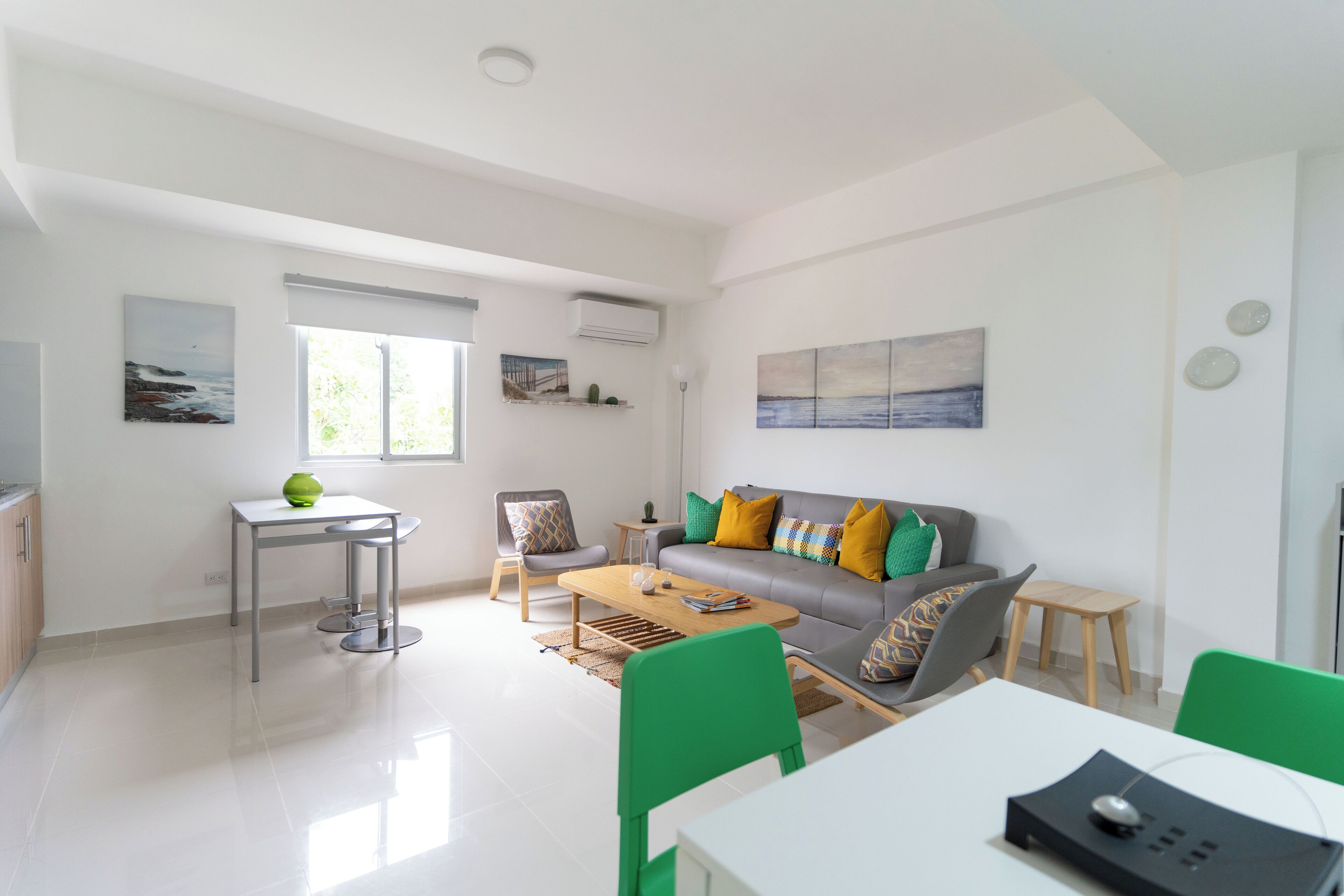 A modern living room with a grey sofa, green chairs, a wooden coffee table, and artwork on the walls.