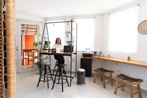 Una cocina moderna con una isla central, taburetes de bar, una planta colgante y un ventanal grande.