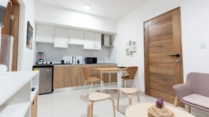 A modern kitchen with white cabinets, a wooden dining table, and two wicker chairs. - Landa Mar Boca Chica (Boca Chica)