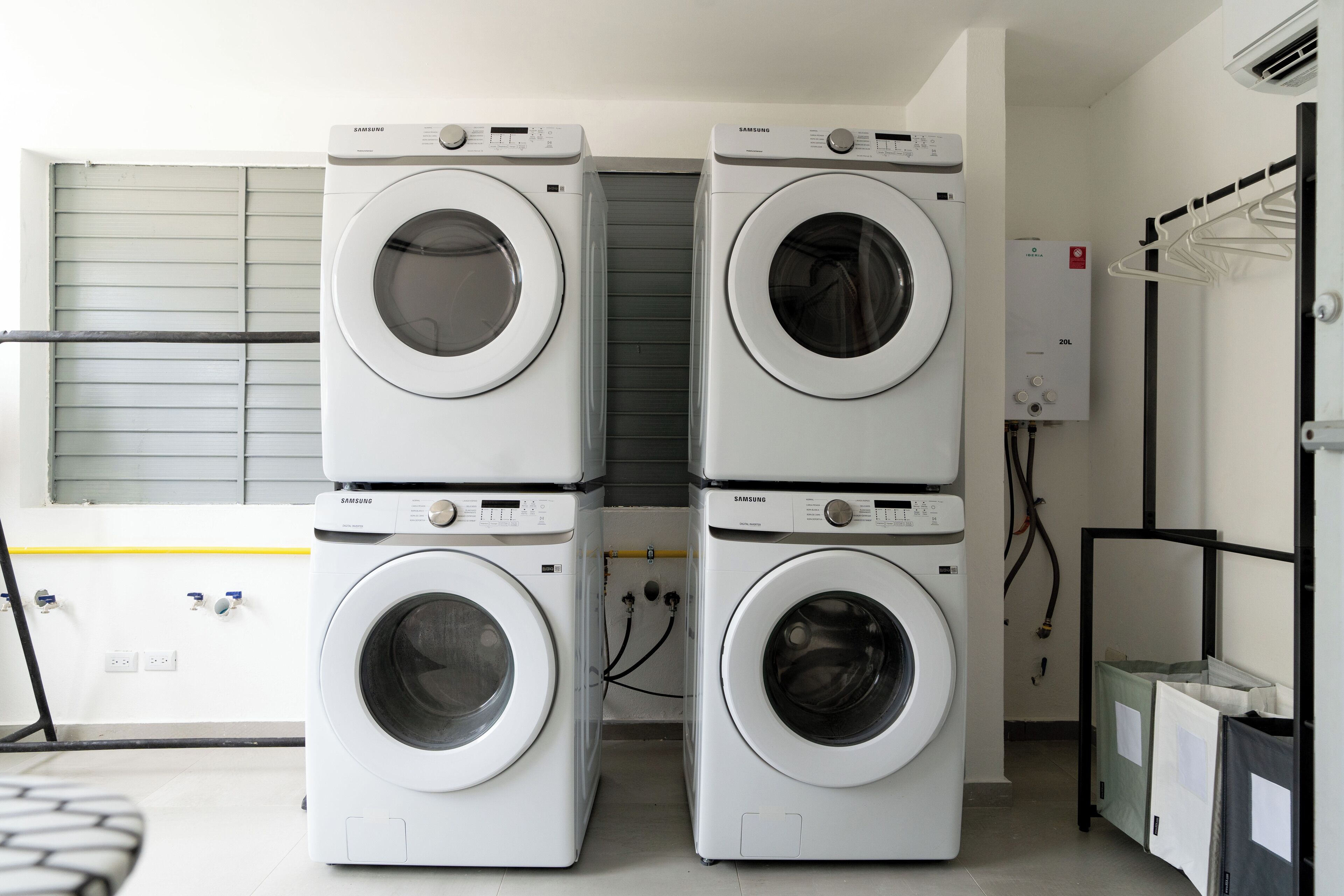 A laundry room with four stacked Samsung washing machines, a dryer, and a water heater.