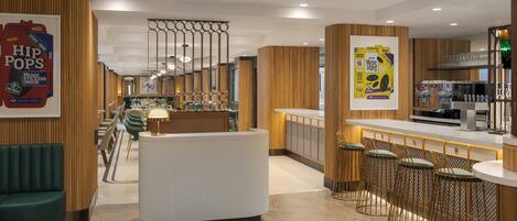 Un espace bar moderne comprenant un comptoir, des tabourets et un coin salon avec un canapé.