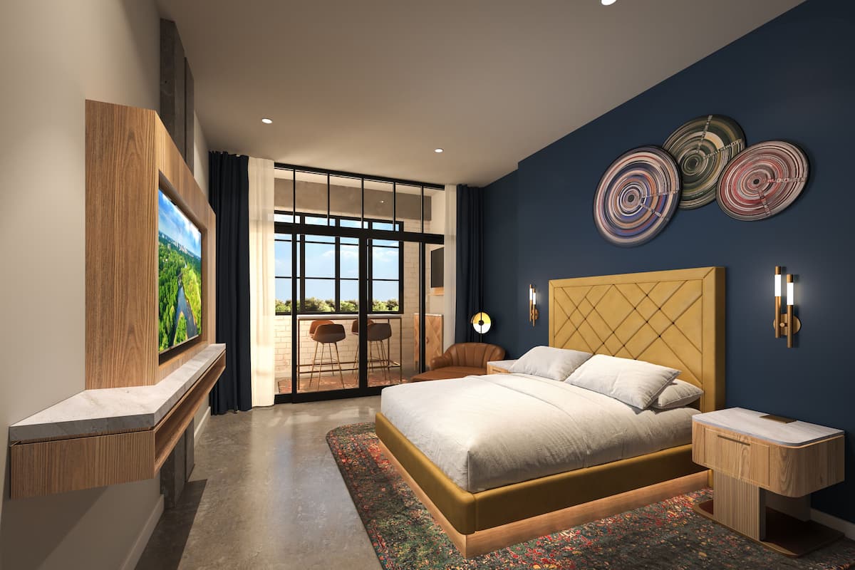 Une chambre moderne avec un grand lit, un téléviseur fixé sur un panneau en bois, un balcon avec des chaises et des œuvres d’art décoratives au mur.