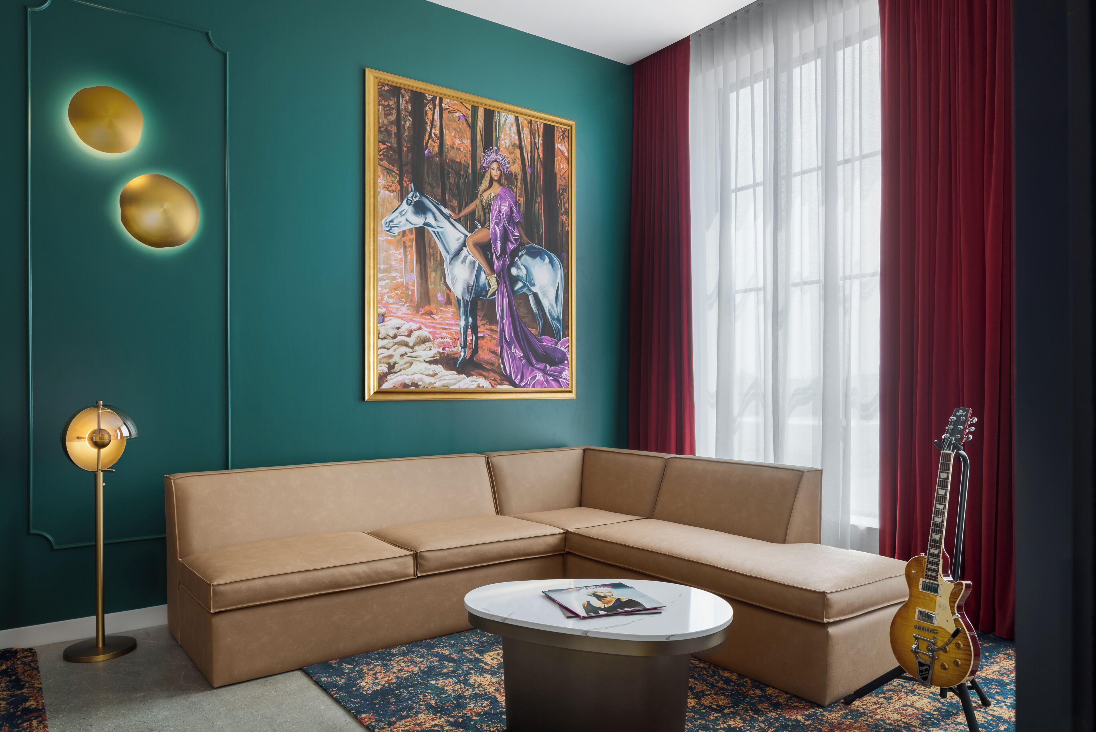 A modern living room with a sectional sofa, a round coffee table, a painting of a woman on a horse, a floor lamp, and a guitar.