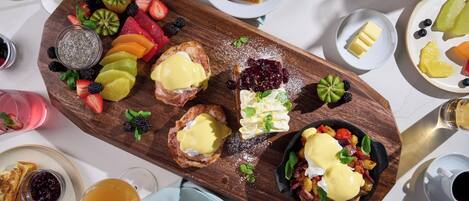 Ein reichhaltiges Frühstücksbuffet mit Toast, Obst und Eiern auf einer Holzplatte.